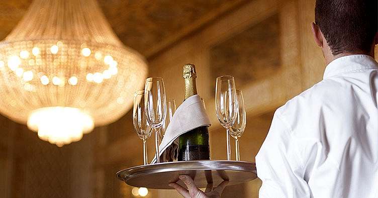 photo of a server carrying a tray with a champagne glasses and a bottle