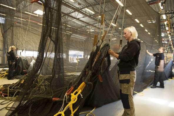 photo of a girl working with a commercial fishing net in a warehouse