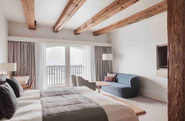 photo of the inside of a bright white hotel room with wood beams on the ceiling