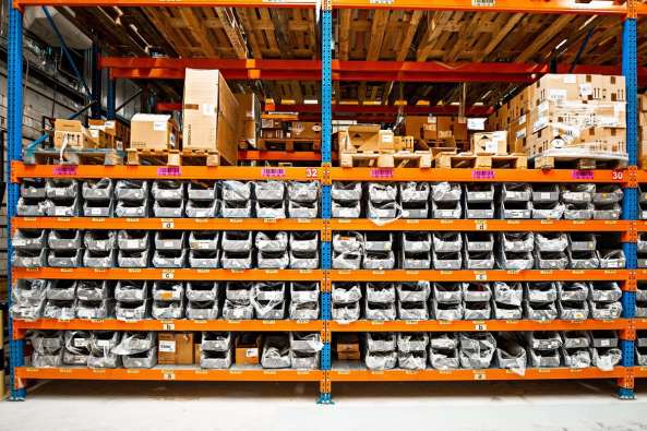 photo of containers on orange shelves inside a warehouse