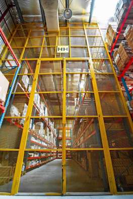 photo to the entrance of a large warehouse with a yellow fence and red shelves