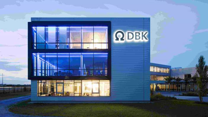 photo from the outside of the DBK headquarters at night with lights on in the building
