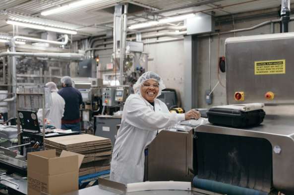 photo of a smiling frontier co op worker packaging boxes in the factory