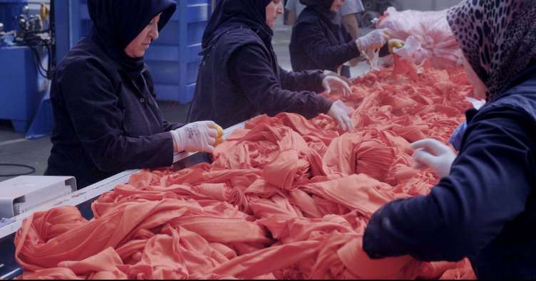 photo of workers with gloves handling orange textiles