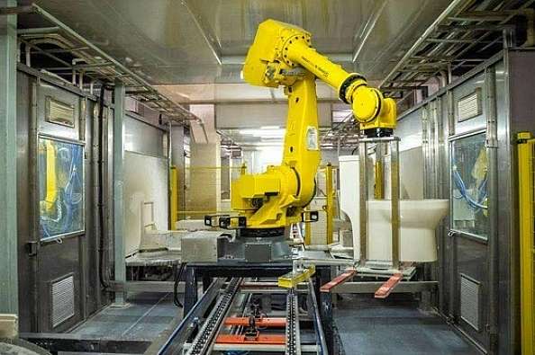 photo of a large yellow robot manufacturing arm in a factory