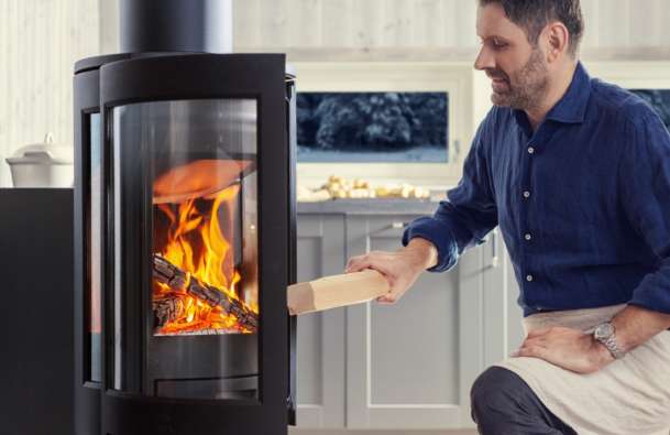 photo of a man putting wood into a jotul stove