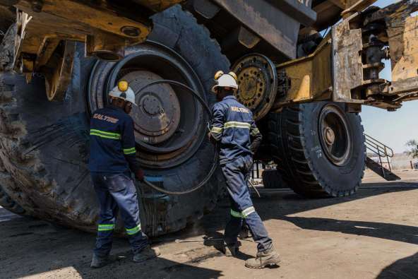 workers assessing large tractor tires