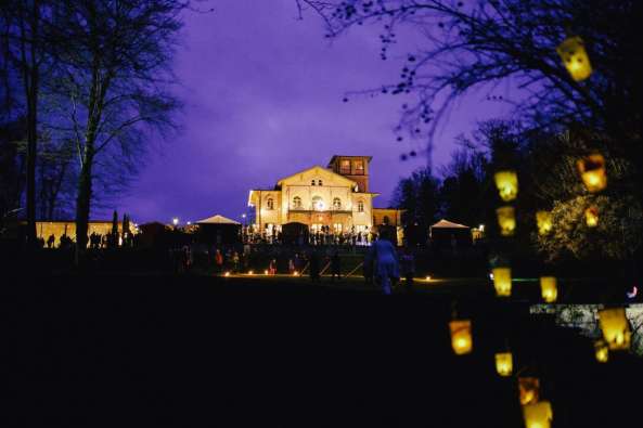 photo of the outside of a large villa lit up at night