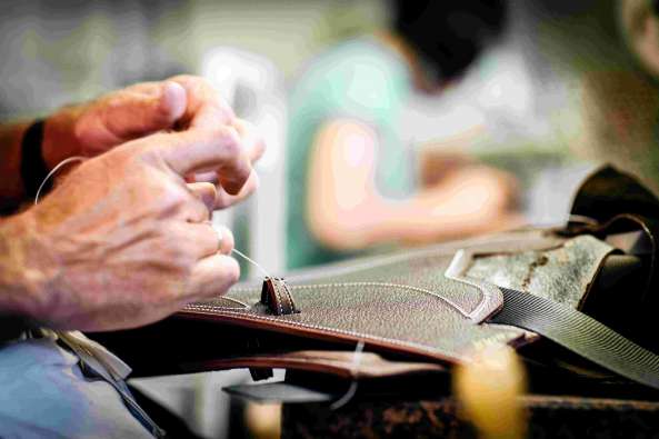 photo of a leathermaker sewing pieces together by hand