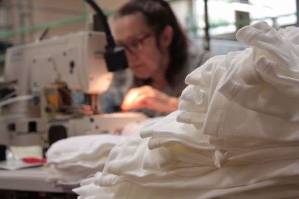 photo of a woman working with a sewing machine and white textiles