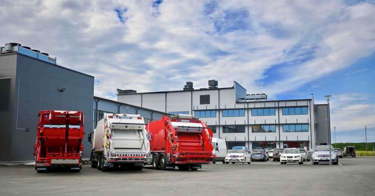 photo of 3 garbage trucks parked at a distribution center