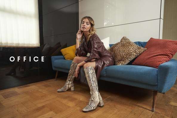 photo of a woman sitting on a couch and wearing snake skin boots in a fashion shoot