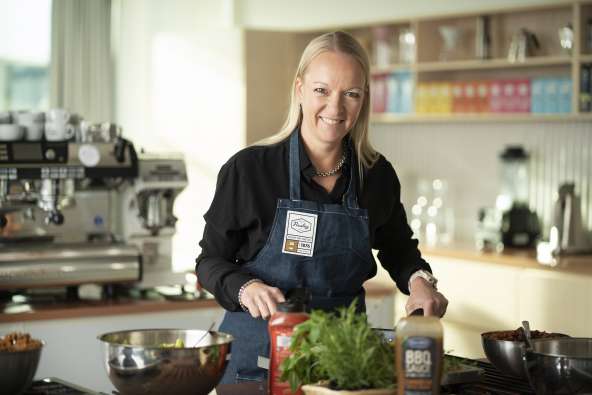 photo of paulig cio Marika Lindström smiling for the camera while cooking in the kitchen