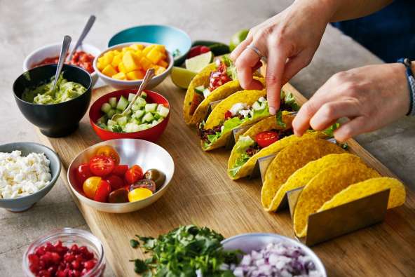 photo of a taco setup with hard taco shells and toppings on a tray
