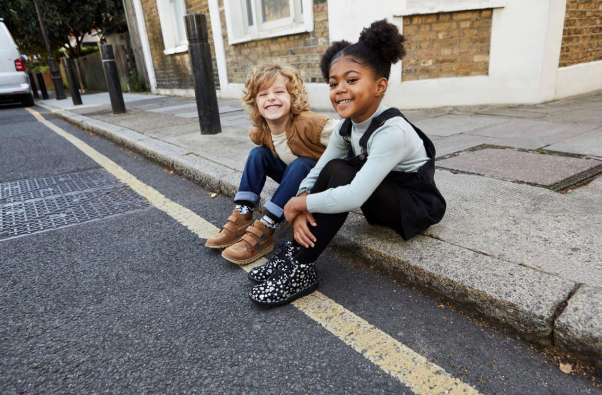photo of two girls sitting on a curb and posing for a photo