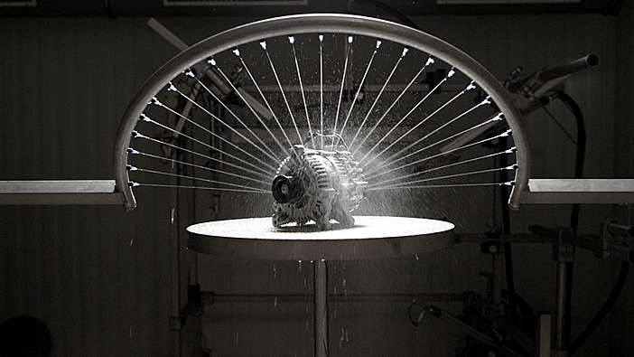 photo of an automotive part being sprayed with water and displayed over a black background