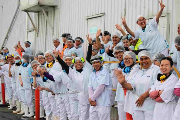 photos of smiling fishery workers dressed in white and wearing protective gear