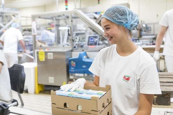 food packaging worker in a white shirt and hair net packaging products