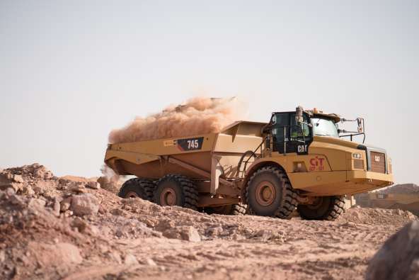 photo of a large cat tractor working and moving dirt in a large quarry