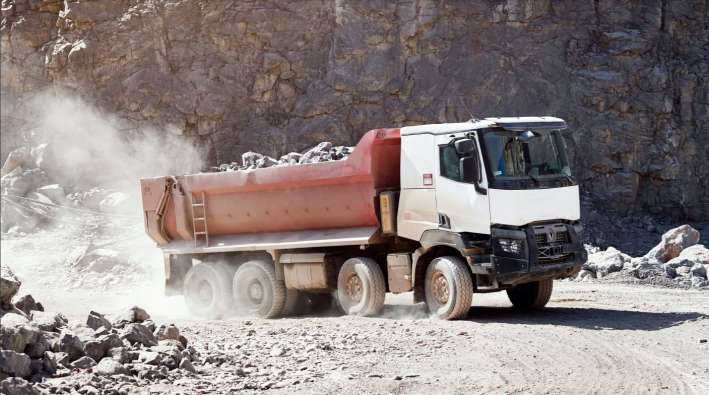 white and red hauling truck carrying rocks out of a quarry