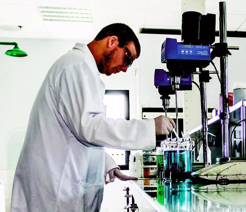 photo of a man in a labcoat working in a lab and mixing chemicals