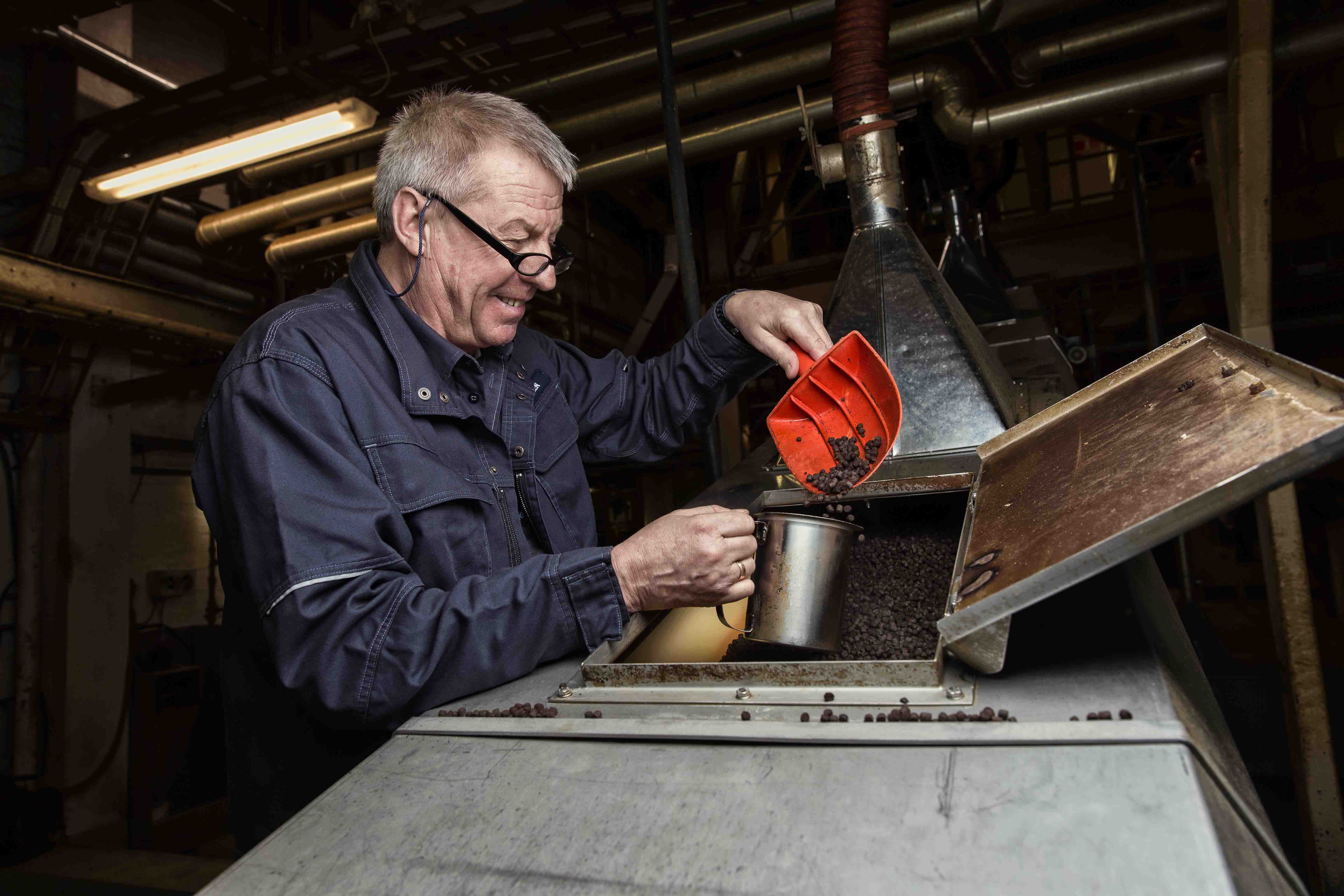 photo of a man scooping up coffee grounds out of a roaster