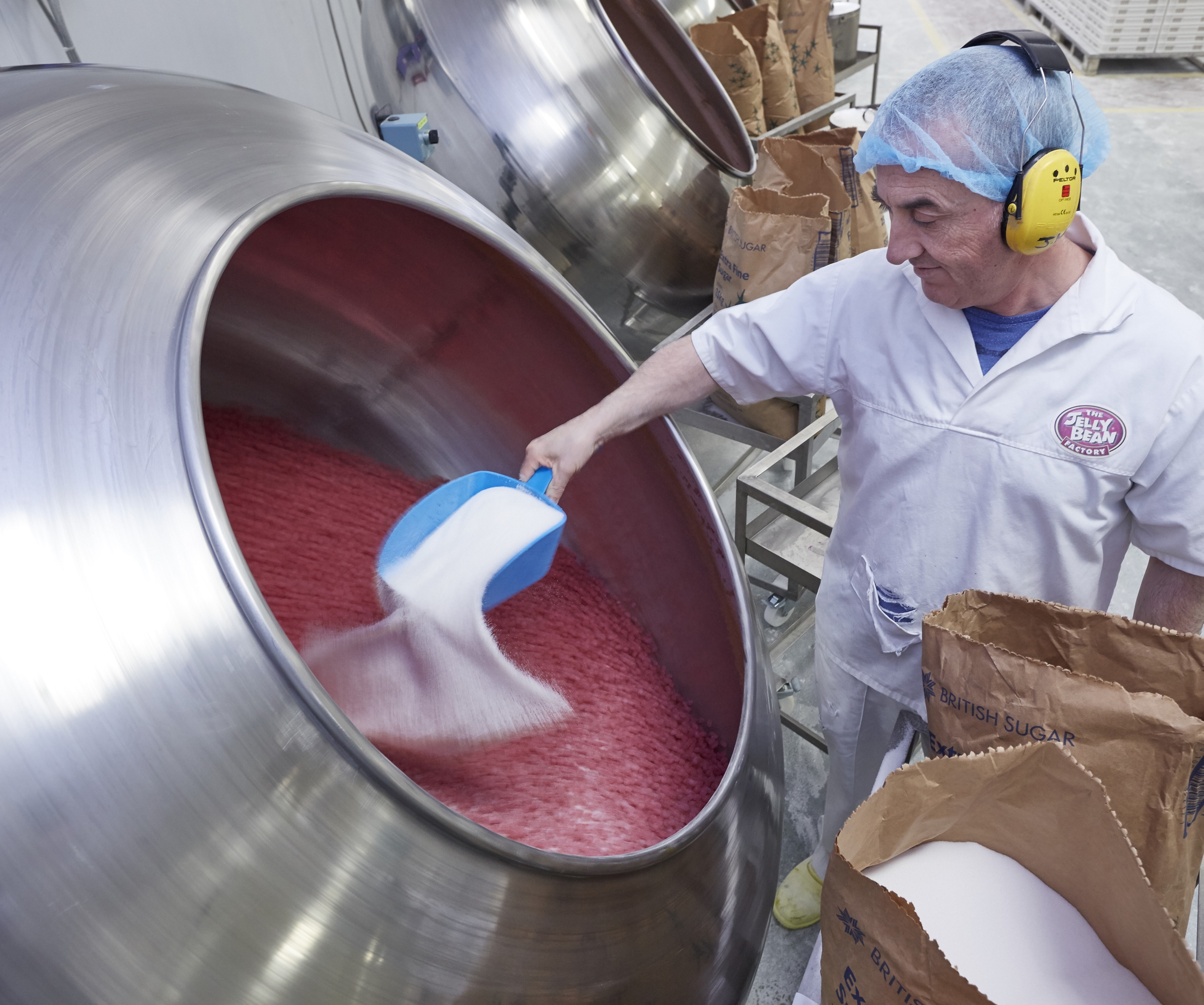 jelly bean maker mixing sugar into the vats of candy