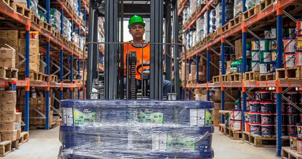 photo of a warehouse worker carrying items around on a forklift