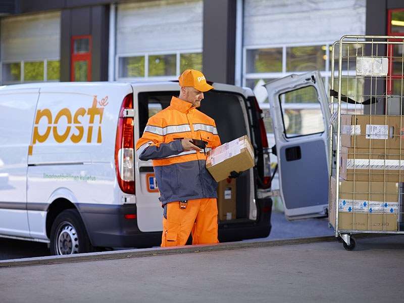 photo of a posti worker in orange gear scanning a package