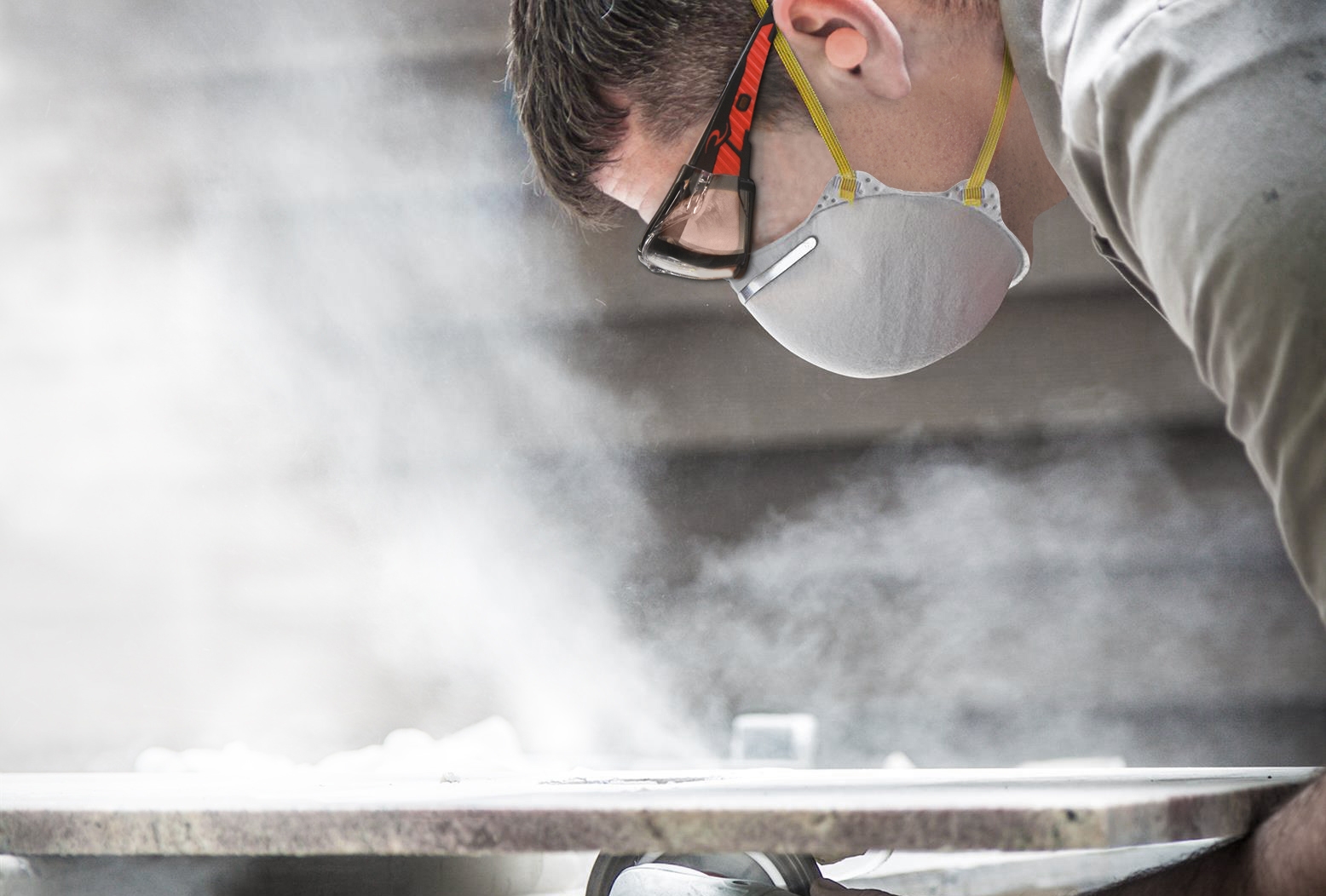 photo of a man wearing goggles and a mask sanding down metal