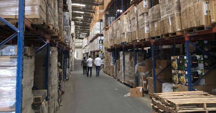 3 men walking through an aisle in a large warehouse