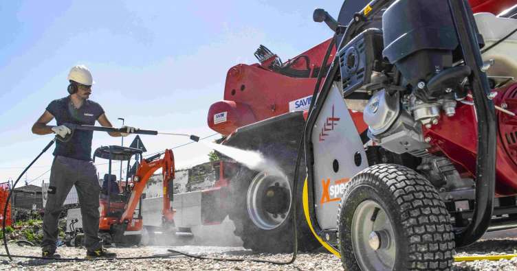 photo of a worker in safety gear power washing a construction tractor