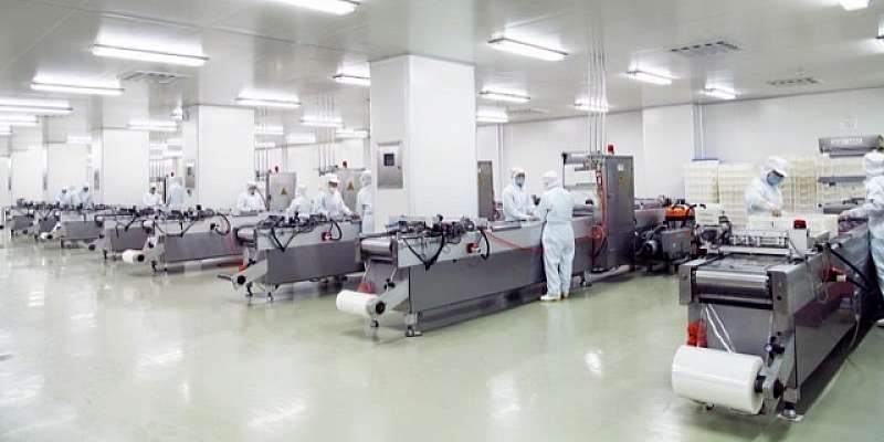 photo of the inside of a food plant with people working in white outfits
