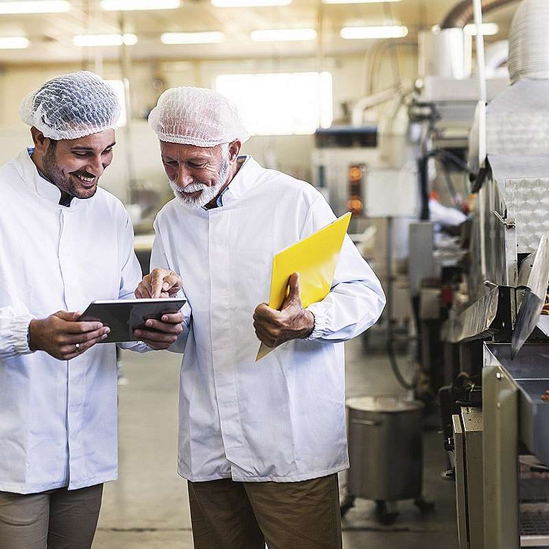 Two food manufacturing workers with modern ERP cloud software helps reduce waste and minimize food safety risks
